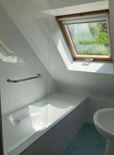 a white bathroom with a sink and a window at Maison Ty Bastian, 100 M² in Saint-Michel-en-Grève