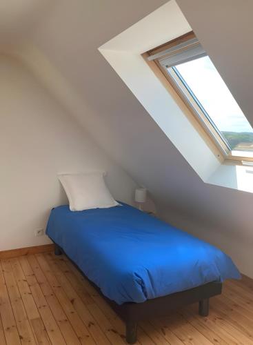 a bedroom with a blue bed in a attic at Maison Ty Bastian, 100 M² in Saint-Michel-en-Grève