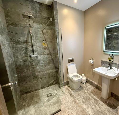 a bathroom with a shower and a toilet and a sink at The Raven Hotel in Corby