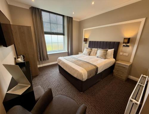 a hotel room with a bed and a window at The Raven Hotel in Corby