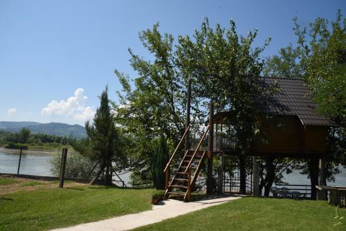 a tree house with a ladder next to a lake at Holiday Home Kućica Na Drvetu in Banja Koviljača