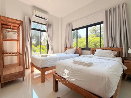 two beds in a room with two windows at Villa La Forest Koh Phangan in Ko Phangan