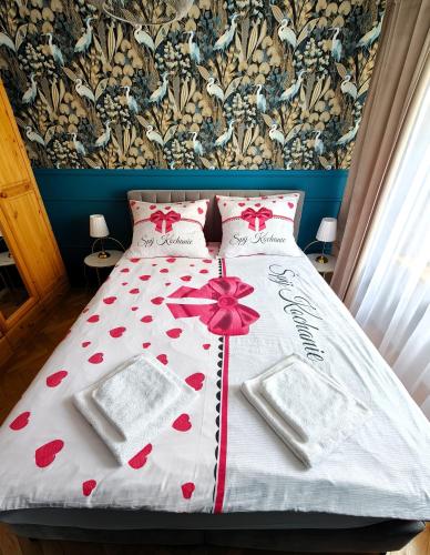 a bed with a white comforter with red hearts at Sen nad Bałtykiem - Apartament z balkonem, Ustka in Ustka
