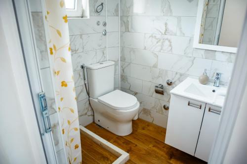 a white bathroom with a toilet and a sink at Apartmani Grbović in Čanj