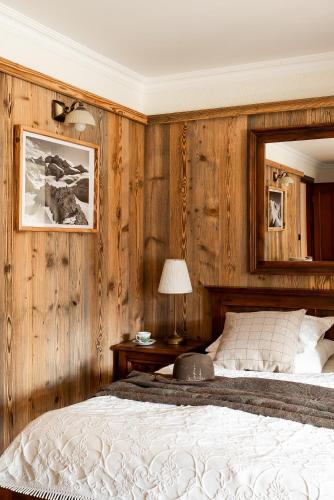 a bedroom with wooden walls and a bed and a mirror at Willa Apart in Zakopane