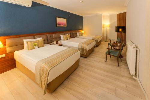 a hotel room with two beds and a desk at Bera Konya Hotel in Konya