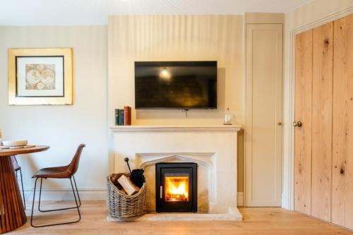 a living room with a fireplace with a tv above it at Beechwood Cottage | Banham Cottages in Bourton on the Water