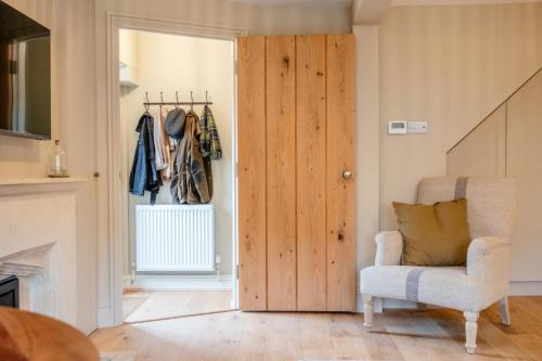 a room with a wooden door and a chair at Beechwood Cottage | Banham Cottages in Bourton on the Water