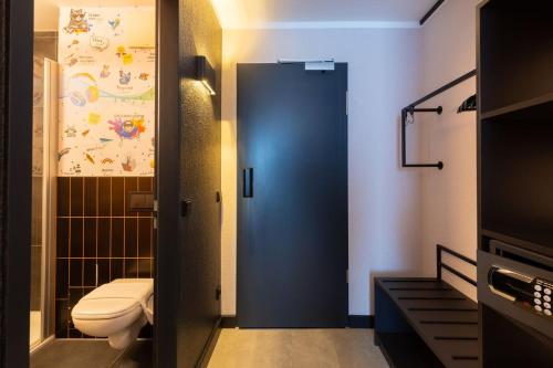 a bathroom with a toilet and a blue door at the niu Clink in Hamburg