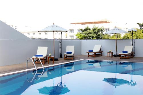 a swimming pool with chairs and umbrellas on a building at Louis Tavern Hotel in Bangkok