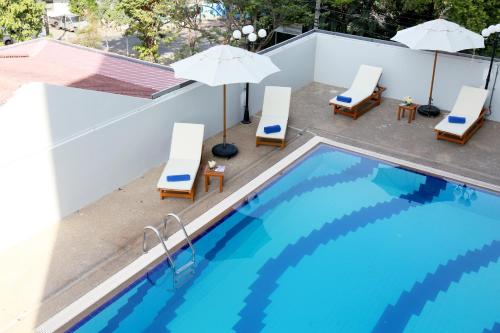 a swimming pool with chairs and umbrellas next to a building at Louis Tavern Hotel in Bangkok