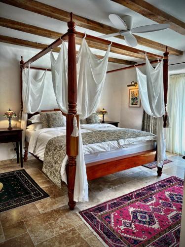 a bedroom with a canopy bed with curtains and a rug at Le Moulin sur Célé - Luxury Villas with Private Pool in Saint-Sulpice
