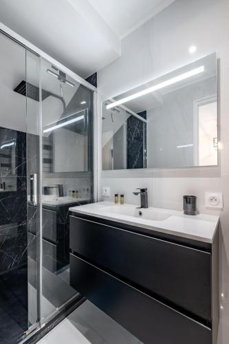 a bathroom with a sink and a glass shower at Appartement Élégant, Climatisation et Piscine in Ormoy-la-Rivière