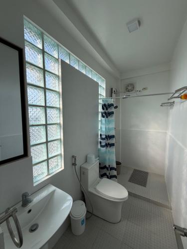 a bathroom with a toilet and a sink and a window at The Coast By RAD in Talisay