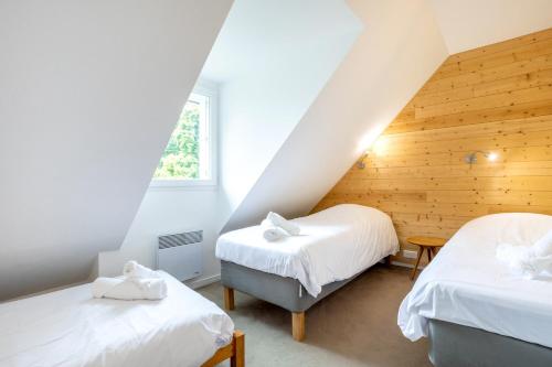 a attic bedroom with two beds and a window at L'Esprit Cap Coz in Fouesnant