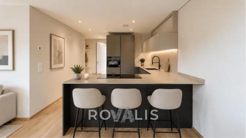a kitchen with a island with white stools at Panorama Apartment Ried-Brig in Ried-Brig
