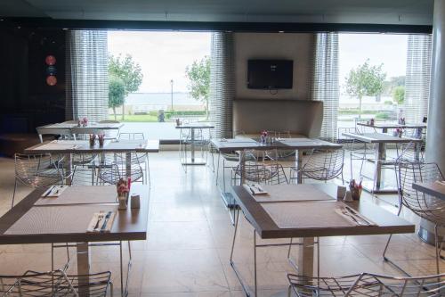 a restaurant with tables and chairs and a large window at Petit Palace Tamarises in Getxo