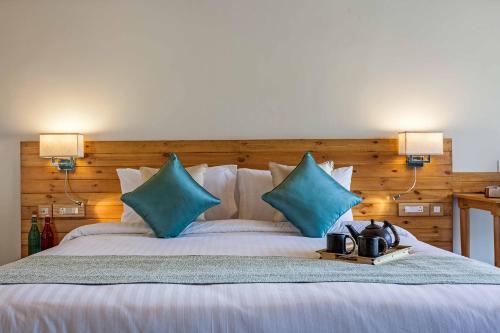 a bedroom with a large bed with blue pillows at Rakkh Resort, a member of Radisson Individuals Retreats in Pālampur