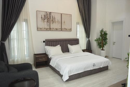 ein Schlafzimmer mit einem großen Bett und einem Stuhl in der Unterkunft White Pole Apartments in Abuja