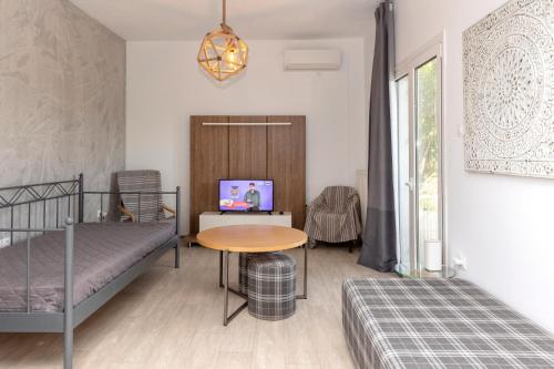 a bedroom with two bunk beds and a table and a tv at Nataly's Gardens with Pool Lagonissi in Lagonissi