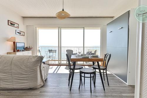 a living room with a dining room table with chairs at Exceptional stay facing the Atlantic Sea-view apartment with balcony in Saint-Gilles-Croix-de-Vie
