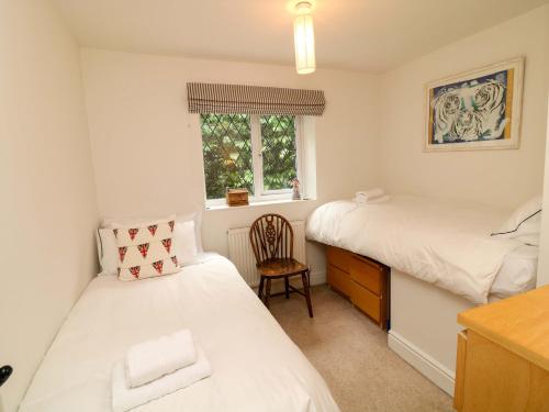 two beds in a room with a desk and a chair at The Chimes in Castleton