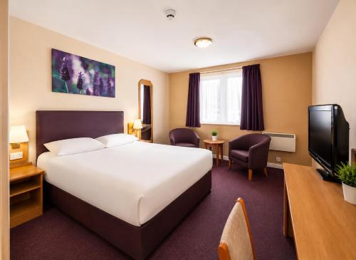 a hotel room with a bed and a flat screen tv at Stables Inn, Aintree in Liverpool