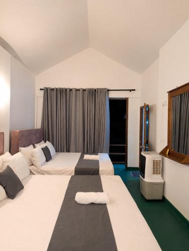 a hotel room with two beds and a television at Visari Fall Villa Ella in Ella
