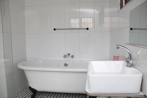 a white bathroom with a tub and a sink at Oria Lodge in Cape Town