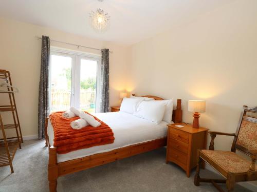 a bedroom with a bed and a chair and a window at The Mill House Gardens in Lowestoft