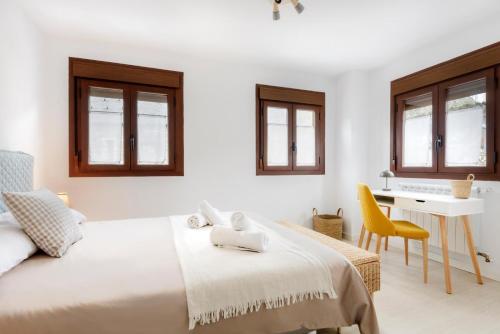 a white bedroom with a bed and a desk at Casa Santiago in Panticosa