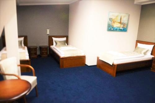 two beds in a room with blue carpet at Hotel Kamienica in Opole