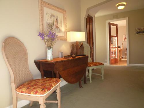 a room with a desk with two chairs and a vase of flowers at Camusmore House in Aviemore