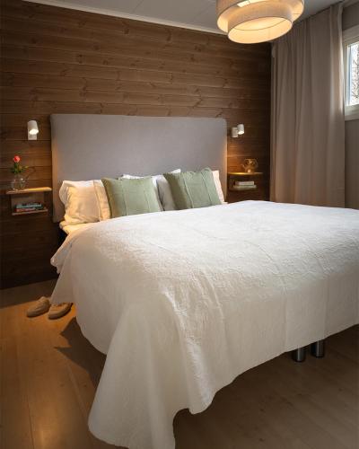a bedroom with a large white bed with a wooden wall at Nordic Lapland Frevisören in Båtskärsnäs