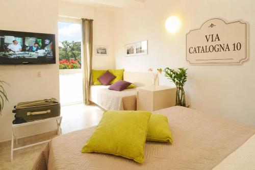 a hotel room with two beds and a tv at Dolce Vita Suite Alghero in Alghero