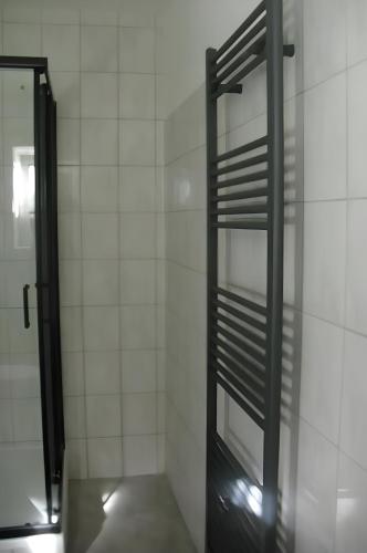 a bathroom with a glass door and a white tiled wall at Gramelowersee in Teschendorf