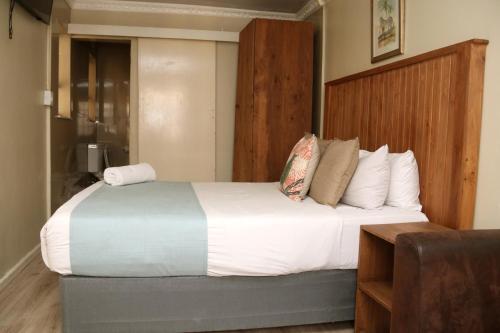 a bedroom with a large bed with a wooden headboard at Oria Lodge in Cape Town
