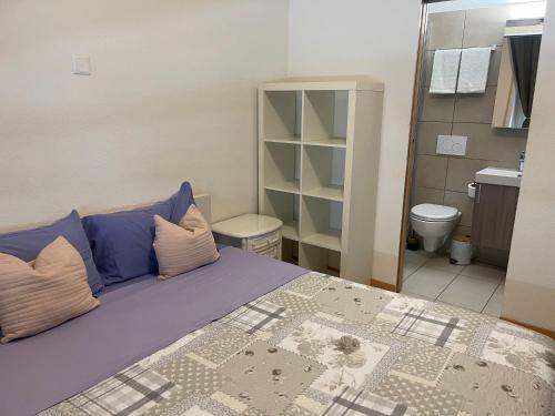 a bedroom with a bed with purple pillows and a bathroom at Balerna Swiss Apartment by RentuGoo Travel in Balerna