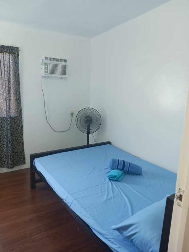 a bed in a room with a fan at 3G's & C Transient House Calapan in Camilmil