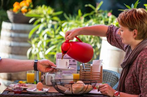 a woman pouring a tea kettle on a table at Pension Julia & Haus Elisabeth - Wallner's Hofheuriger & Weinhof in Mörbisch am See