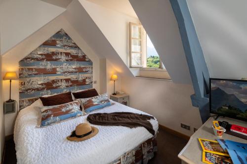ein Schlafzimmer mit einem Bett, auf dem ein Hut liegt in der Unterkunft Hotel Le Viscos in Saint-Savin