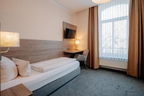 ein Hotelzimmer mit einem Bett und einem Fenster in der Unterkunft Parkhotel Lingen by Hackmann in Lingen