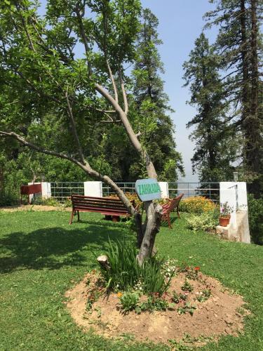 a sign on a tree in a park with a bench at The Hermitage Kanatal in Kanatal