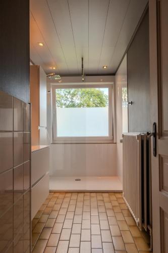 a bathroom with a window and a tile floor at Gîte Ô16 in Nassogne
