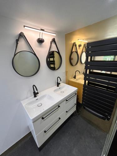 a bathroom with a sink and two mirrors on the wall at Gite Les Oliviers d'Ardèche in Chalencon