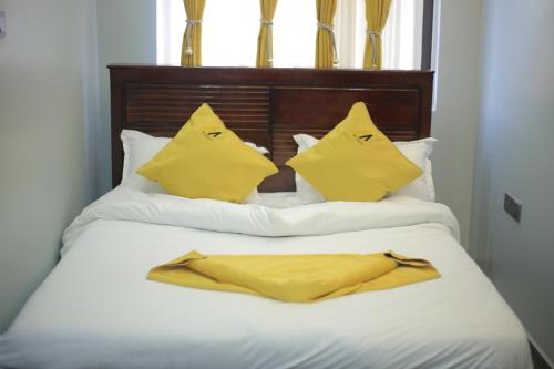 a bed with two yellow pillows at Mignon Hotel - Kalule in Kalule