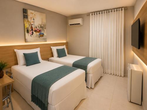 a hotel room with two beds and a tv at Hotel Cantinho Verde in Teixeira de Freitas