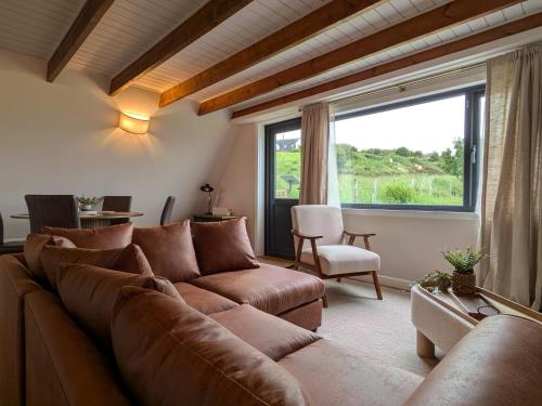 a living room with a couch and a large window at The Chalet, Kildonan in Edinbain