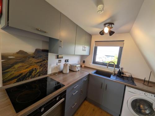 a kitchen with a sink and a washing machine at The Chalet, Kildonan in Edinbain