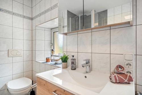 a white bathroom with a sink and a toilet at Kleines Stadthaus mit Sauna in Hillesheim